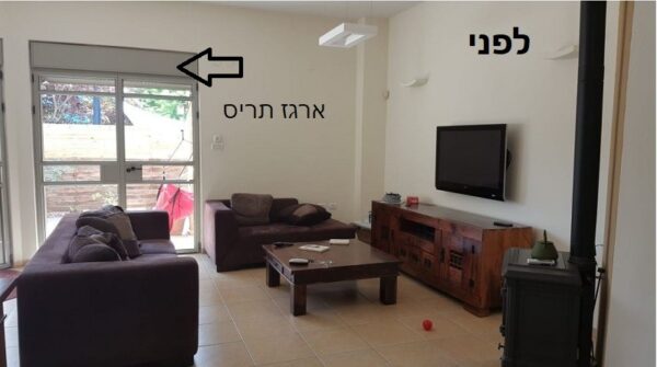 סלון מעוצב עם ספות, מזנון עץ, גופי תאורה תלויים וחלון גדול המכניס אור טבעי.